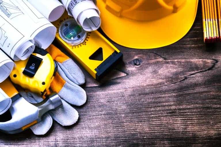 Above All Construction displays a generic image of tools, a hardhat, and architectural and building plans that would be used in a variety of general contracting projects, highlighting their strong capability as a chosen general contractor in the Kansas City region.